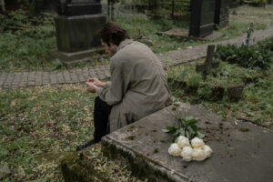 Man dealing with grief and loss thinking in a graveyard